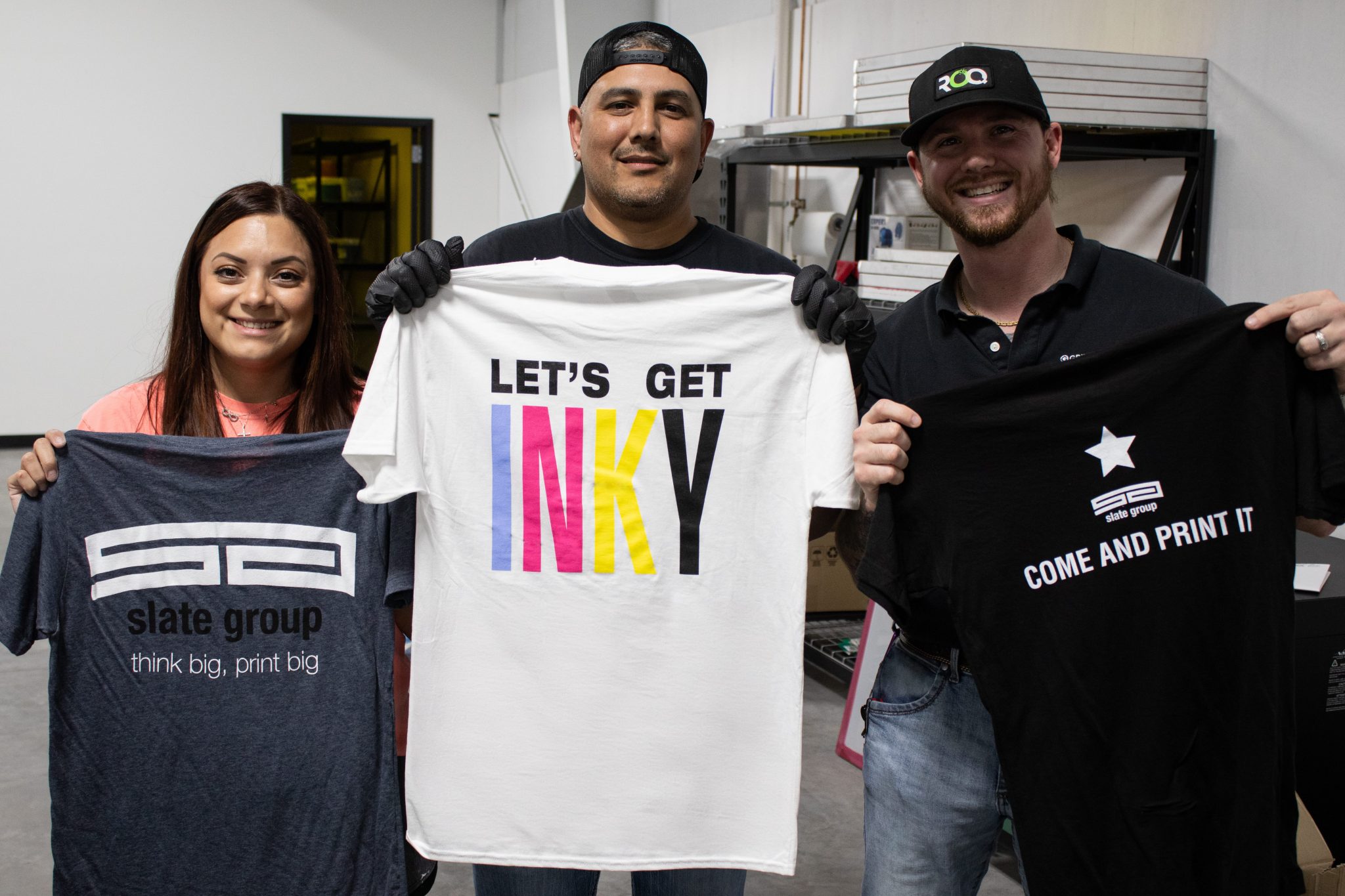 Slate Group production team holding colorful screen printed shirts